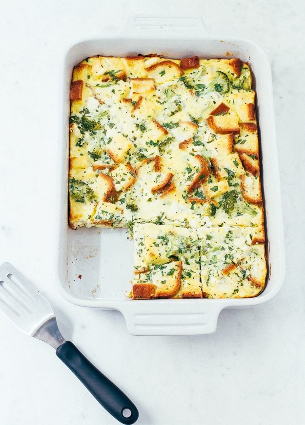 Baking pan of a breakfast casserole. Sliced, and one piece has been taken out. Spatula to the side.