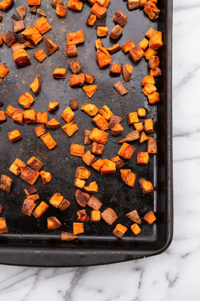 Crunchy sweet potato croutons spread out on a baking stone.