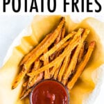 Oval bowl lined with parchment paper and filled with crispy baked sweet potato fries. A small bowl of ketchup is in the next to the fries.