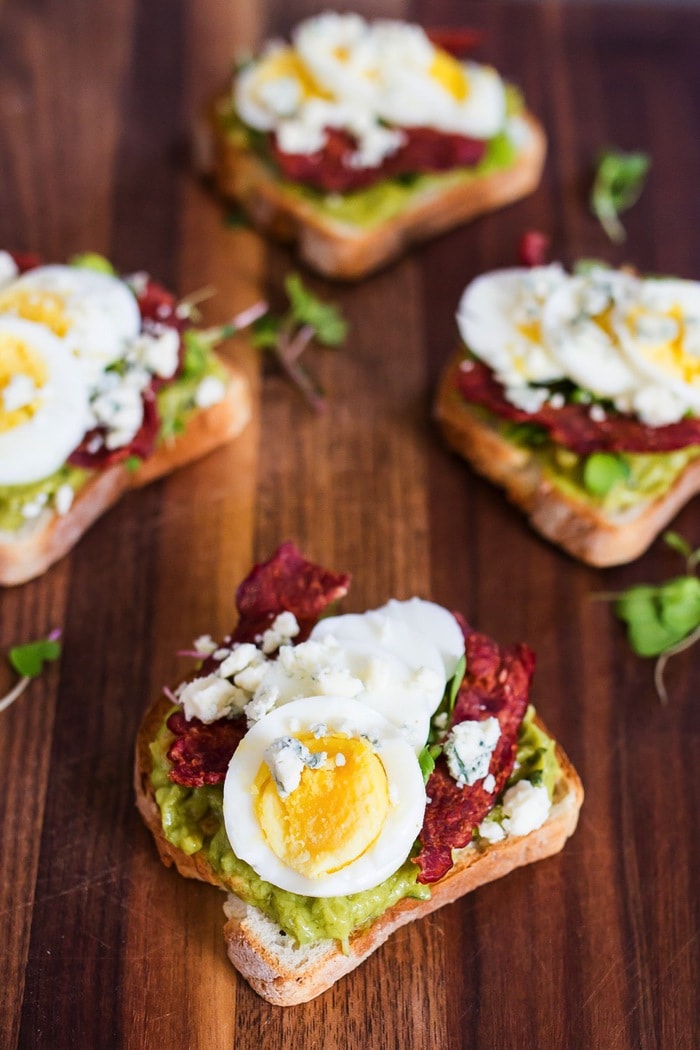 Four slices of toast with Cobb salad avocado topping.