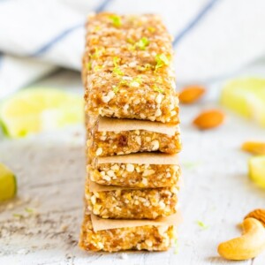 Key lime pie Larabars stacked with parchment in between each. The top bar has lime zest on top.