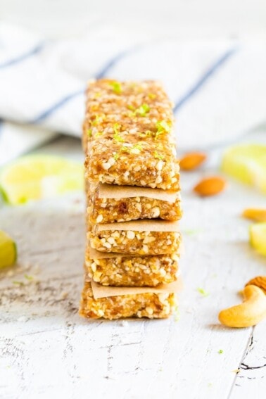 Key lime pie Larabars stacked with parchment in between each. The top bar has lime zest on top.