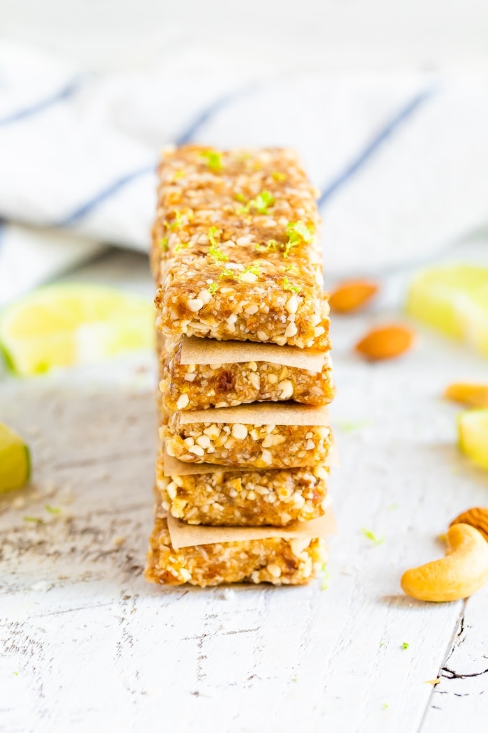 Key lime pie Larabars stacked with parchment in between each. The top bar has lime zest on top.