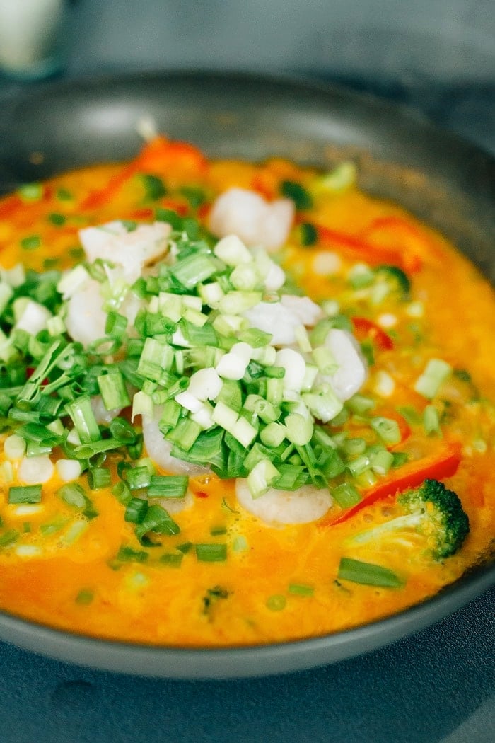 Thai Shrimp Curry Cooking in a pan with chopped veggies.