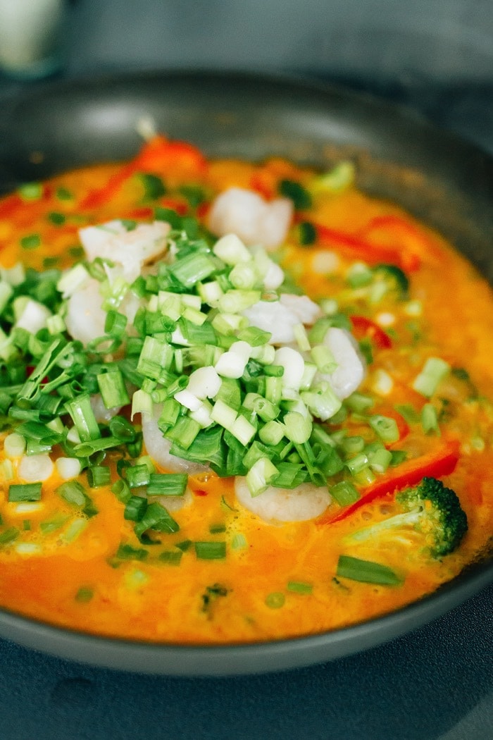 Thai Shrimp Curry Cooking in a pan with chopped veggies.