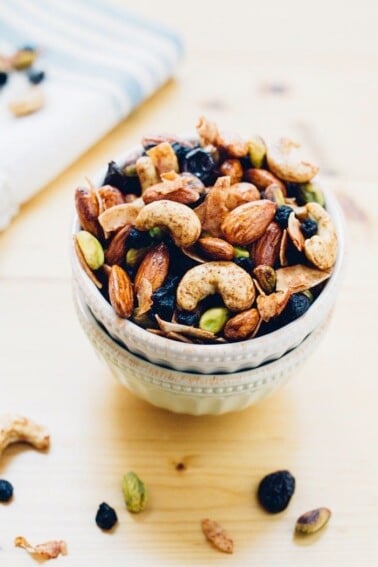 Two bowls stacked, full of trail mix with mixed nuts and dried blueberries.