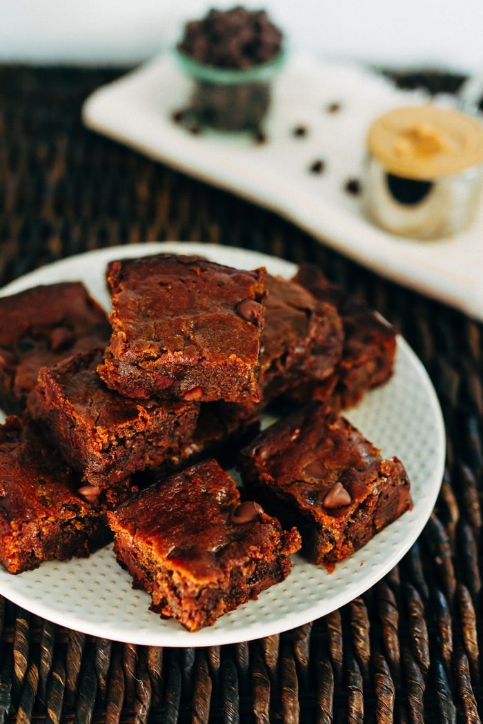 A plate with peanut butter hummus brownies stacked on top.