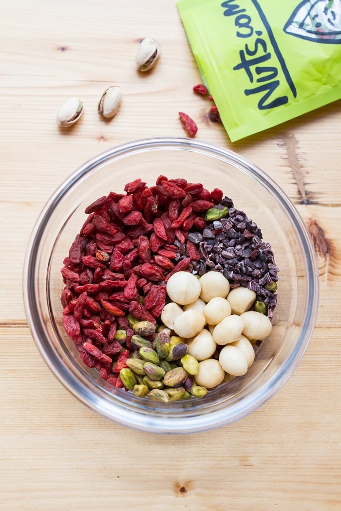 Snack healthy with this crunchy, vibrant pistachio trail mix. It’s a delicious blend of roasted pistachios, macadamia nuts, goji berries and cacao nibs. A bowl of ingredients for pistachio trail mix.