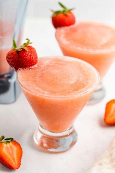 Two glasses with strawberry frosé. Each one has a strawberry on the rim.