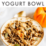 Bowl filled with yogurt and pumpkin and topped with seeds, granola and almond butter. Spoon and pumpkin off to the side.