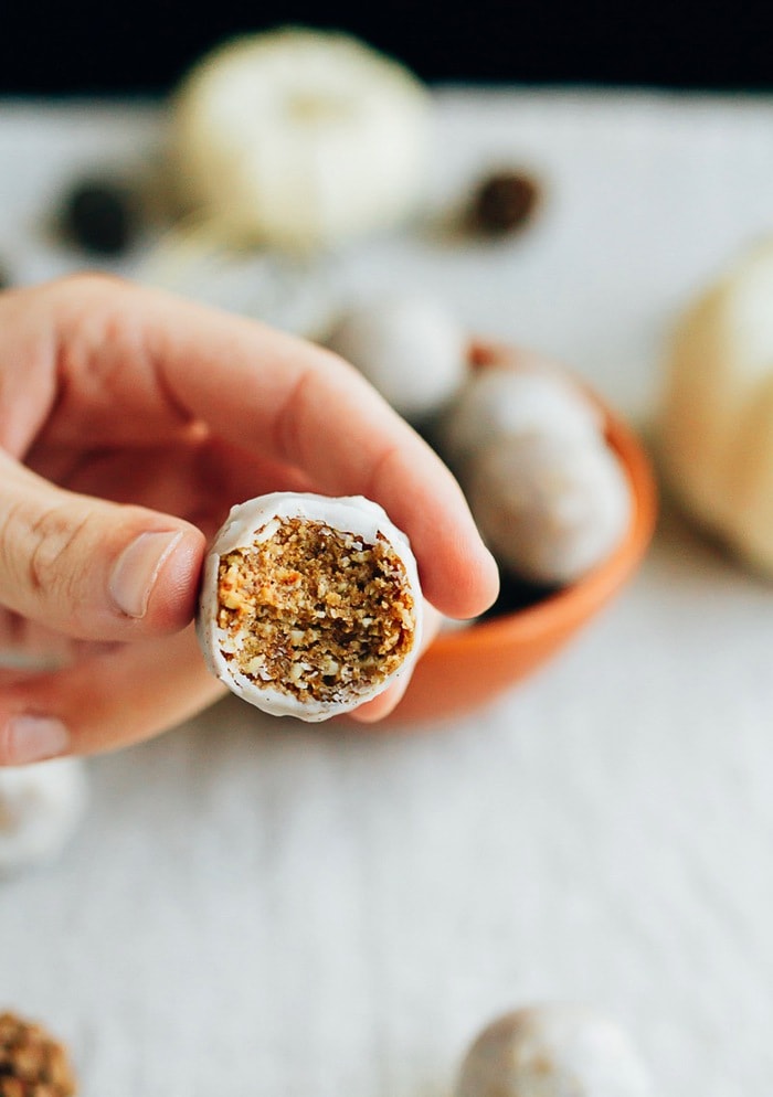 Hand holding a pumpkin spice donut hole with a bite taken out of it.