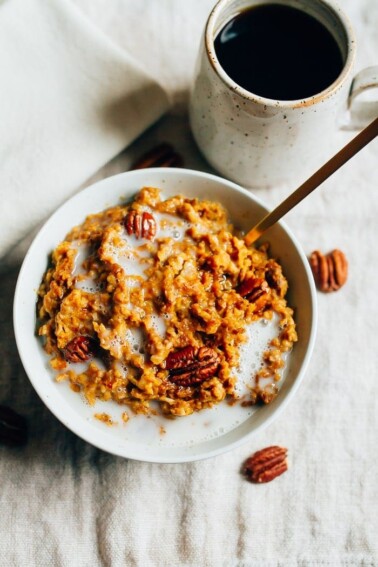 Overhead shot of Slow Cooker Pumpkin Pie Oatmeal in a white bowl with milk and pecans in the bowl.