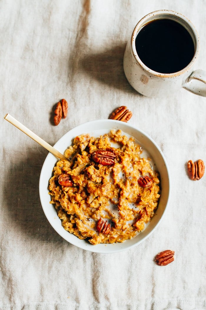 Overhead shot of Slow Cooker Pumpkin Pie Oatmeal in a white bowl with pecans scattered around the bowl. 