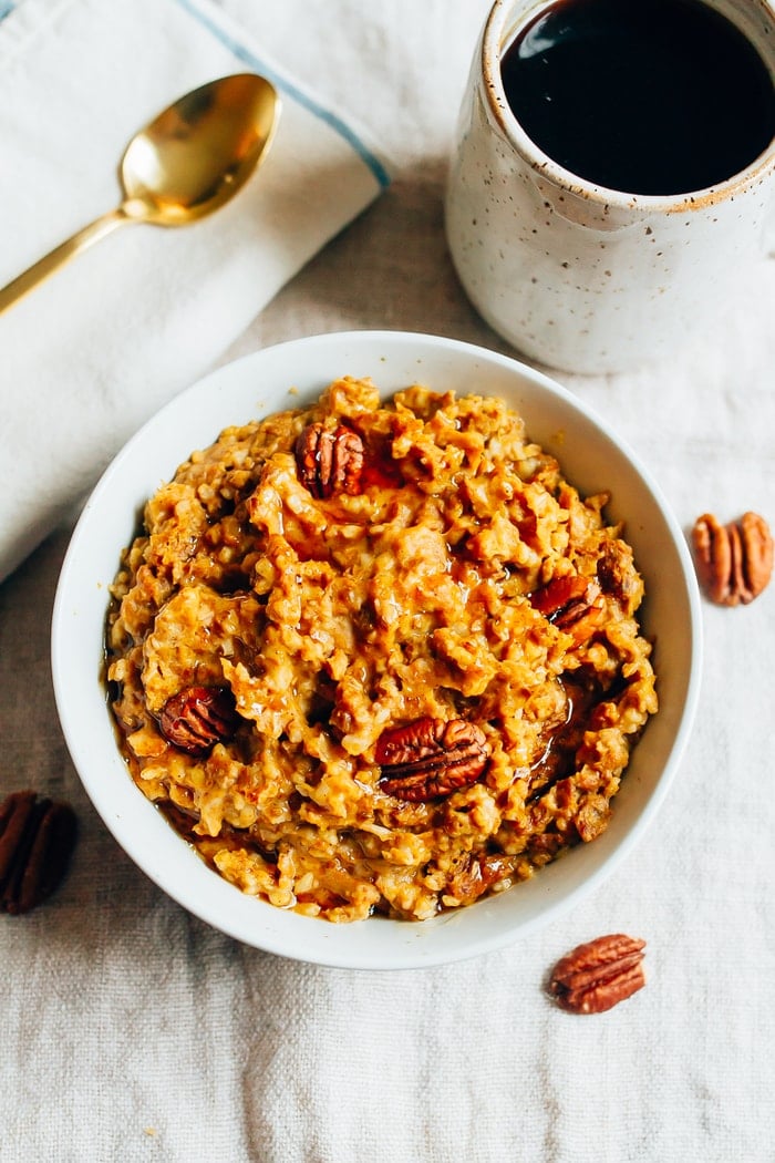 Overhead shot of Slow Cooker Pumpkin Pie Oatmeal in a white bowl. Mug of coffee in the background.