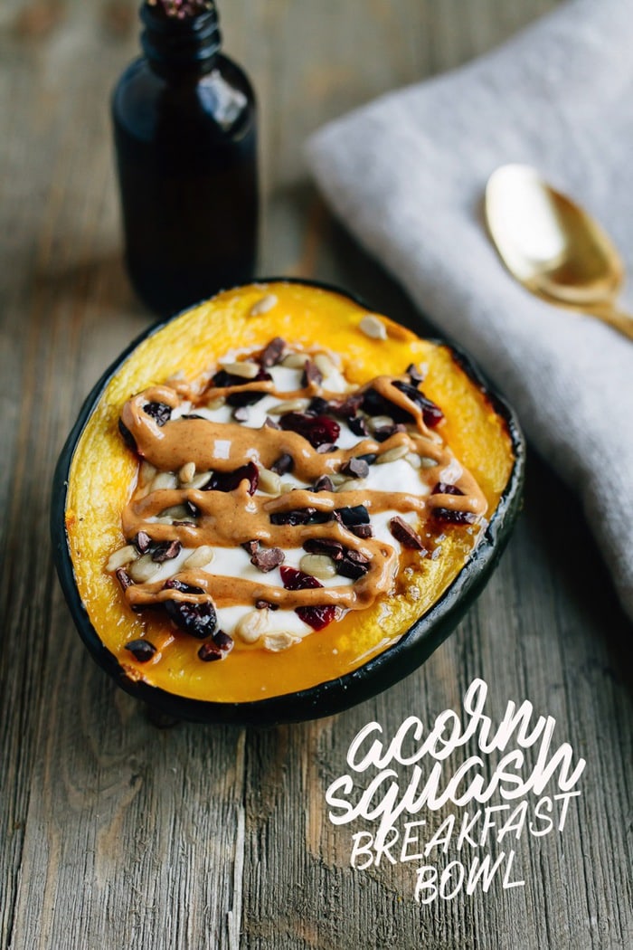 Roasted acorn squash breakfast bowls served warm with yogurt, cranberries and seeds, drizzled with peanut butter.