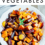 Caramelized, roasted root veggies like carrots, sweet potatoes, parsnips, and onions in a serving bowl on a wood table. Text above says "roasted root vegetables".