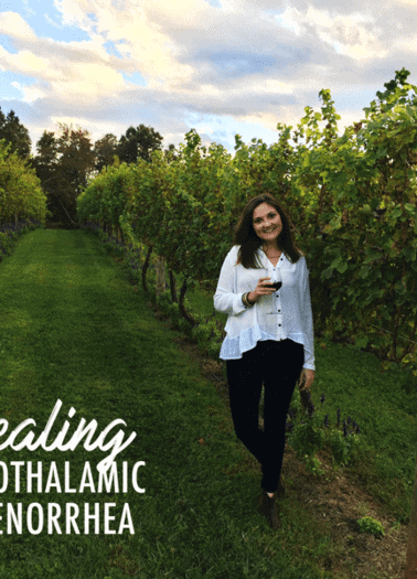 Woman smiling with wine glass in a vineyard with the words healing hypothalamic amenorrhea written out next to her.