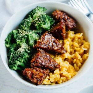 Bowl of yellow rice with tempeh and broccoli.