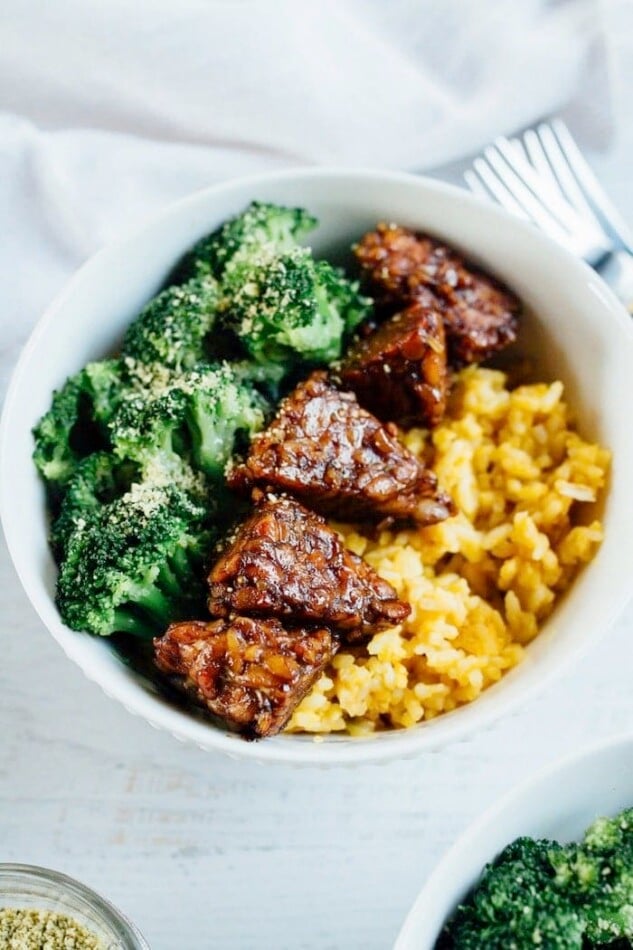 Bowl of yellow rice with tempeh and broccoli.