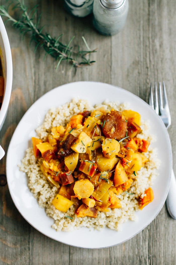 Root vegetable tagine with rosemary and apricots served over a plate of brown rice.