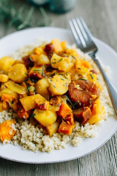 Root vegetable tagine over quinoa on a white plate with a fork.