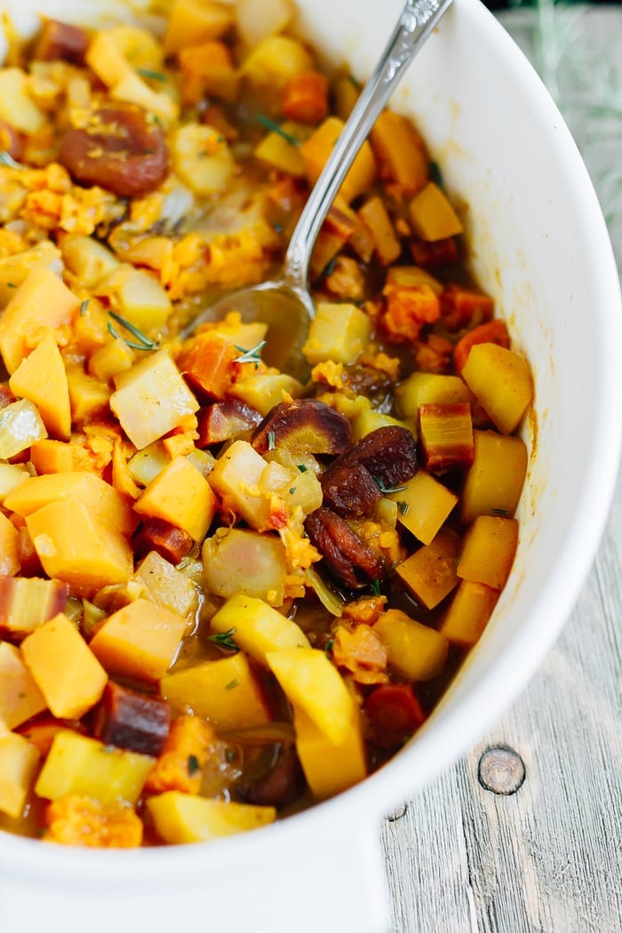 Roasted root vegetables in a dish with dried apricots and topped with rosemary.