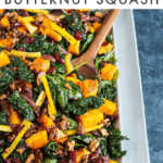 Holiday kale salad with butternut squash, kalamata olives, walnuts, cranberries and peppers on a serving platter.