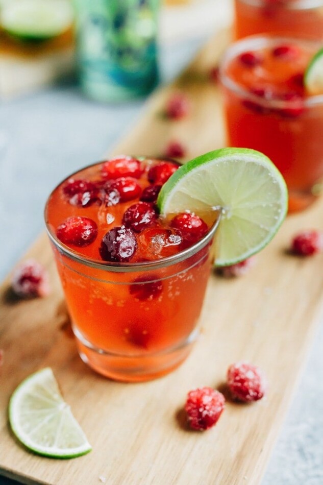 Sparkling Vodka Cranberry with Lime and Sugared Cranberries on a cutting board surrounded by the ingredients.