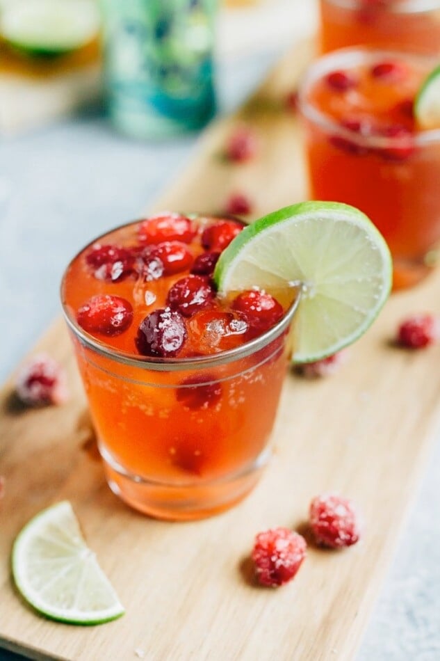 Sparkling Vodka Cranberry with Lime and Sugared Cranberries on a cutting board surrounded by the ingredients.