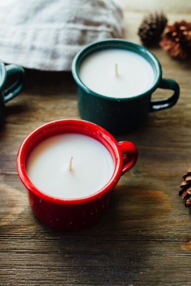 Mini enamelware candles in a red mug and green mug.