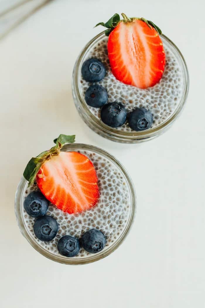 Chia pudding in small mason jars with berries on top.