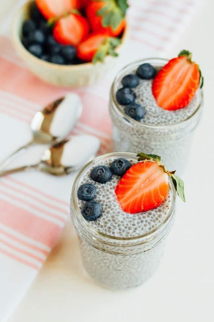 Chia pudding in mason jars with blueberries and strawberries on top.