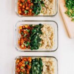 Three glass containers, each with rows of curried chick peas, garlic sautéed spinach, and white rice.