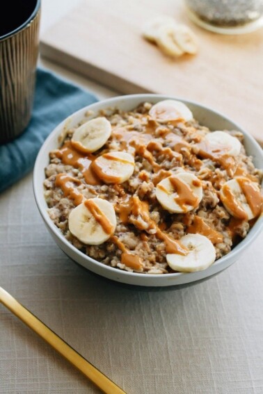 Bowl of oatmeal with chopped bananas and drizzled peanut butter on top.
