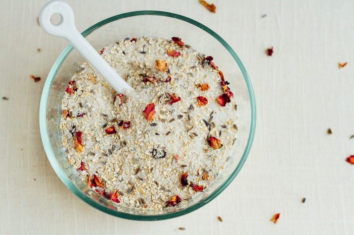 DIY lavender rose bath soak in a glass bowl with a white spoon. 