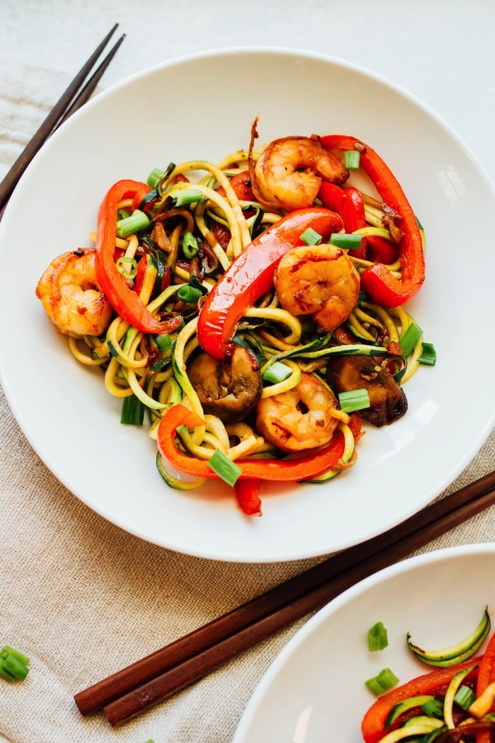 White bowl with healthy zucchini noodle and shrimp lo mein. 