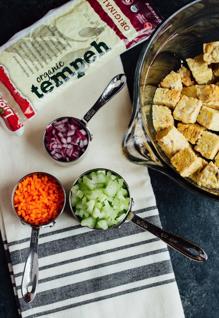 Ingredients in measuring cups for the tempeh salad, chopped carrots, onion and celery.