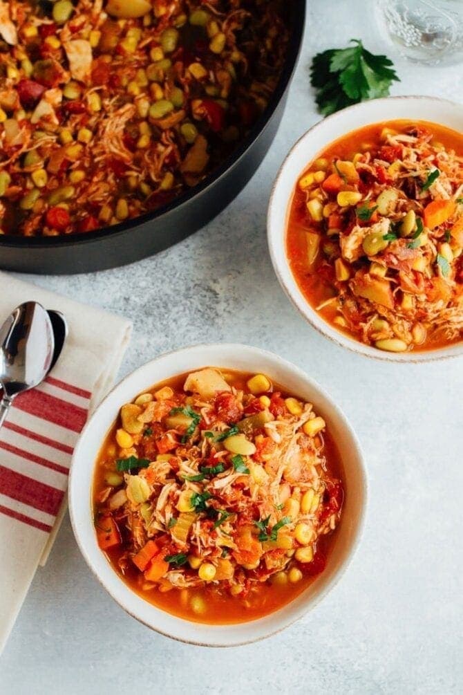 Two bowls and a large pot of Brunswick stew.