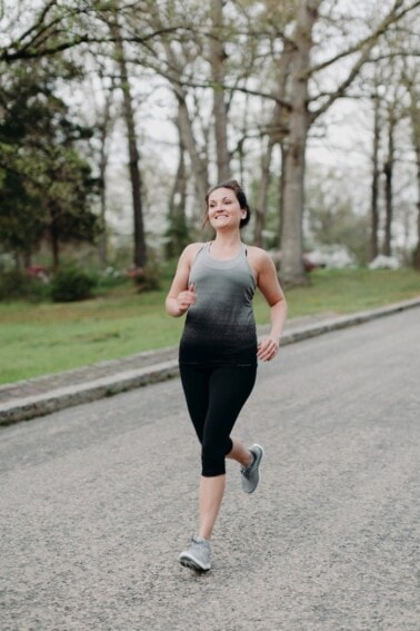 A woman smiling and running outside.