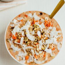 Carrot cake overnight oats with nuts and shredded coconut in a bowl with a spoon.