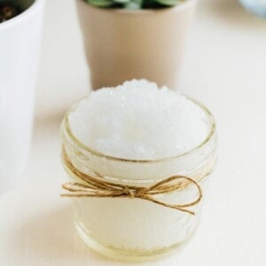 Small mason jar wrapped with twine and filled with peppermint foot scrub with succulents in the background.