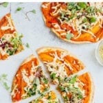Tortilla pizzas topped with vegan cheese, peppers and greens and hummus.