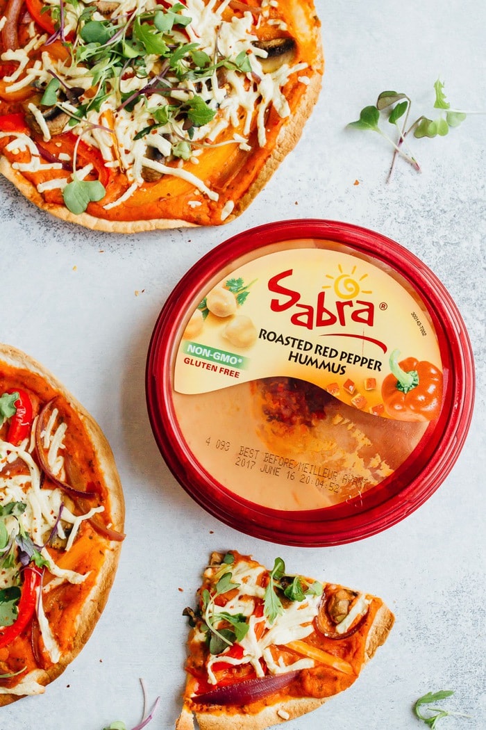 Get creative on pizza night with these thin and crispy vegan tortilla pizzas with hummus. They're easy, personal-size (for instant portion control) and delicious! Sabra roasted red pepper hummus next to tortilla pizzas.