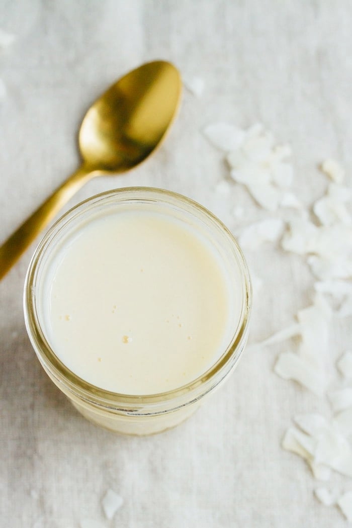 Coconut butter in a small mason jar with a gold spoon on the left. 
