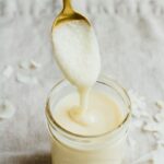 Coconut butter in a small mason jar with a spoonful on a gold spoon.