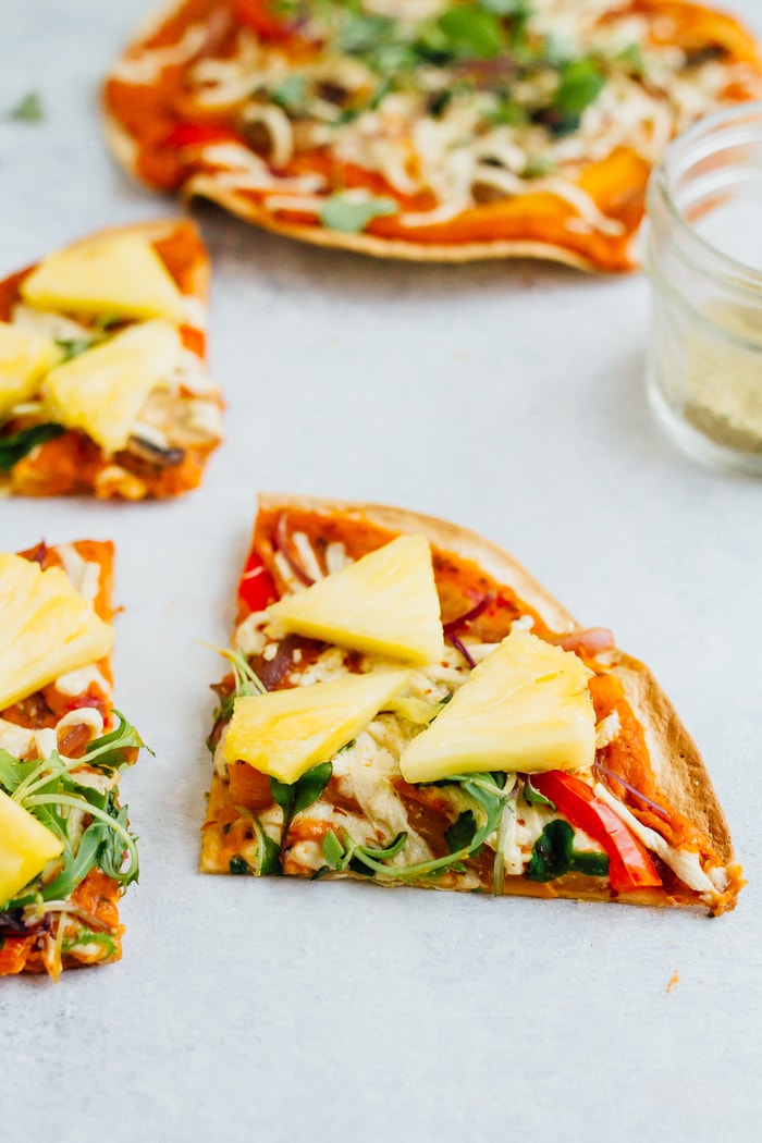 Hummus tortilla pizza topped with vegan cheese, veggies and pineapple.