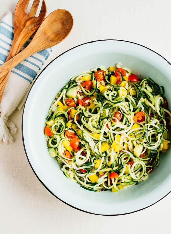 zucchini noodle spaghetti salad in a bowl with wooden salad tongs