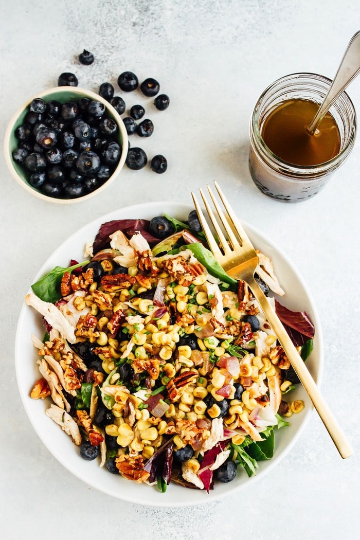 Blueberry corn chicken salad in a white bowl with a gold fork. 