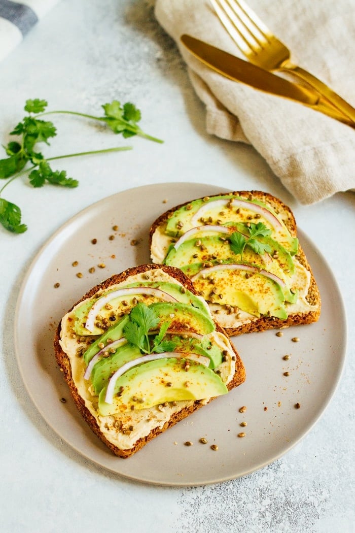 Hummus avocado toast makes for a quick and easy breakfast or snack idea. Load up each slice with red onion, cilantro and toasted hemp seeds for extra flavor and crunch. Hummus avocado toast makes for a quick and easy breakfast or snack idea. Load up each slice with red onion, cilantro and toasted hemp seeds for extra flavor and crunch.