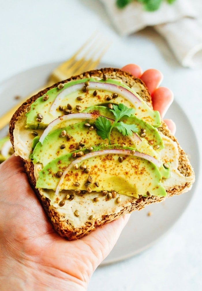 Hummus avocado toast makes for a quick and easy breakfast or snack idea. Load up each slice with red onion, cilantro and toasted hemp seeds for extra flavor and crunch. 